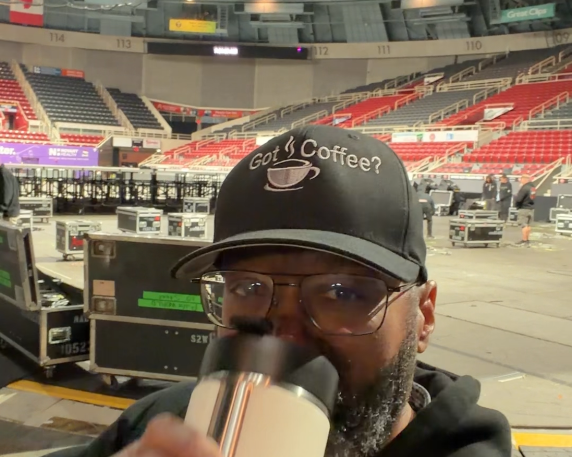 Person holding a microphone in an indoor sports arena.